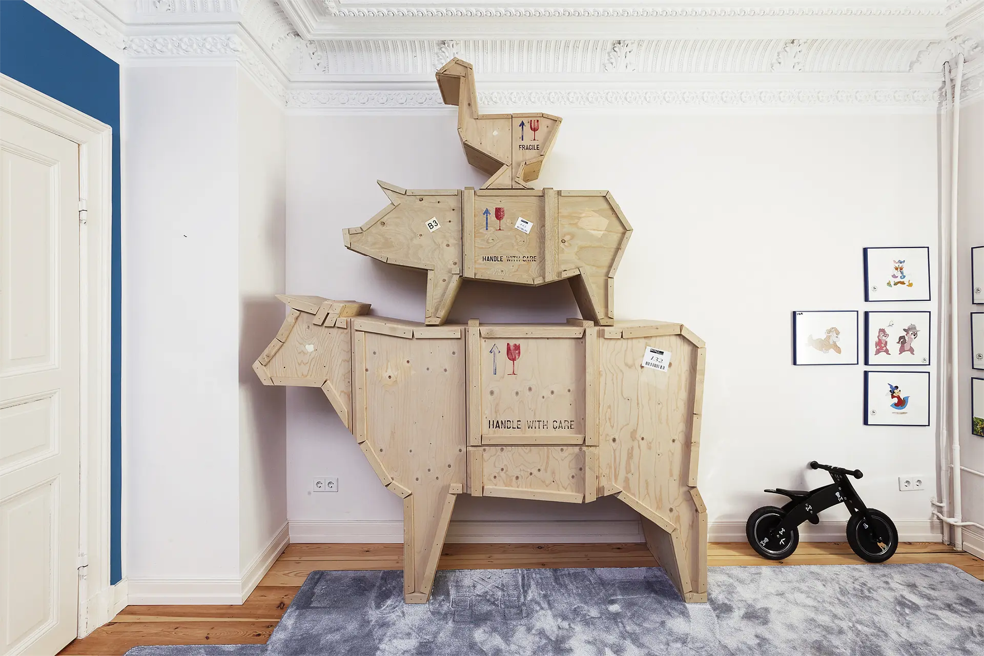 Ulrich Weinkath – Altbau 1900 – Kinderzimmer mit Schrank In einem Kinderzimmer stehen drei übereinander gestapelten Schrankelemente aus Altholz. Der Schrank hat die Form einer abgewandelte Variante der Bremer Stadtmusikanten.