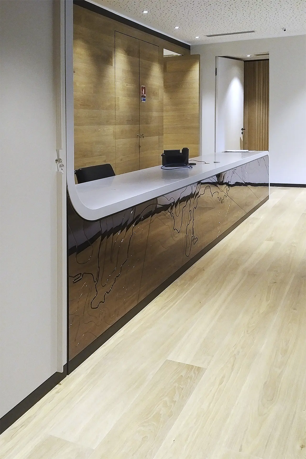 Ulrich Weinkath – Office – Empfangstresen frontal Blick auf die glänzende Vorderseite eines Empfangstresen. Dieser ist aus Mineralwerkstoff.