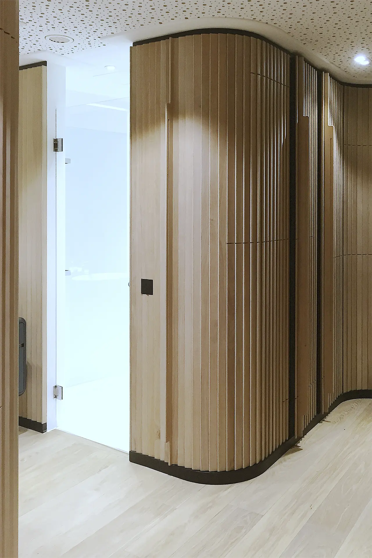 Ulrich Weinkath – Office – Wandverkleidung mit Duschtür Holzfarbene Wandverkleidung mit Duschtür aus Glas.