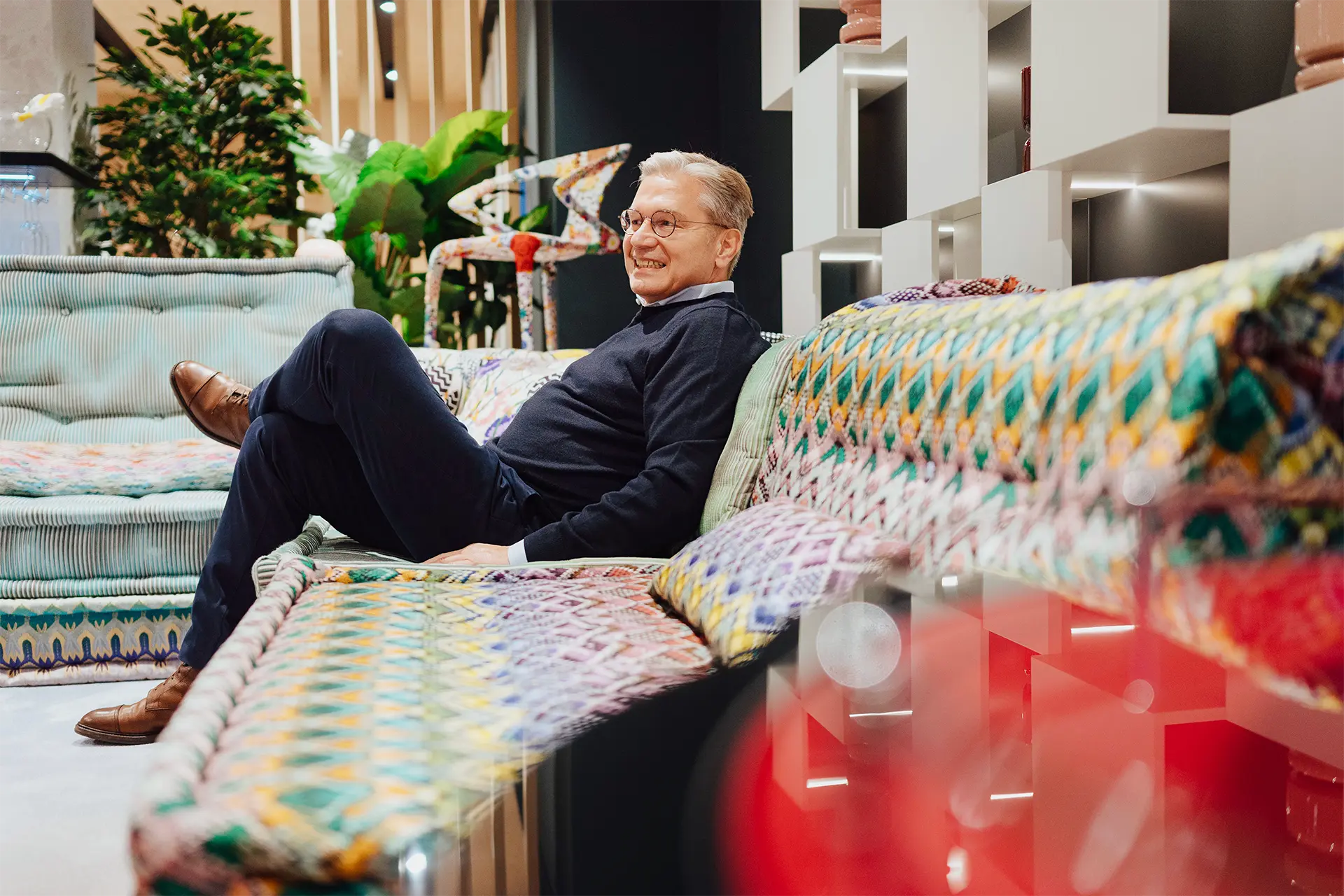 Ulrich Weinkath – Besuch in einem Showroom am Neuen Wall auf Sofa Ulrich Weinkath sitzt auf einem buntem Sofa in einem Interior-Showroom am Neuen Wall. Er lächelt.
